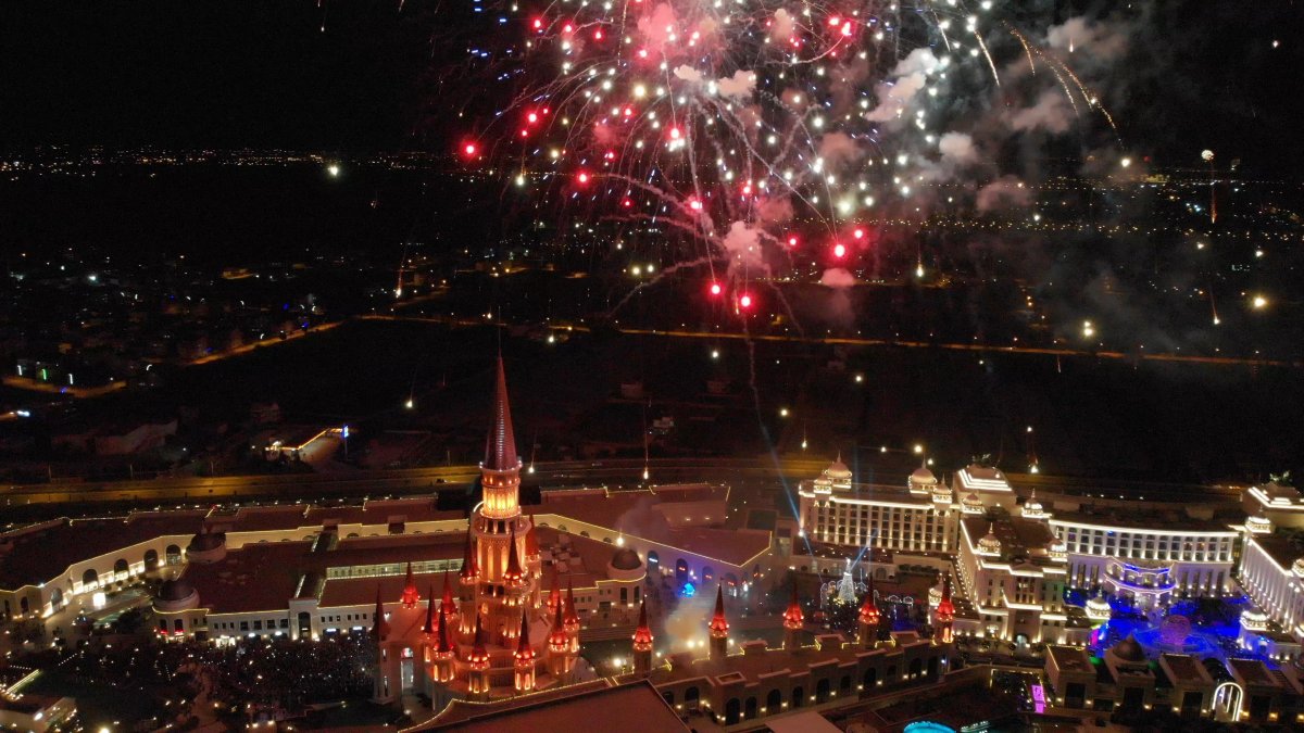 Havai fişekler altında aydınlatılmış tema parkı ve gece gösterisi